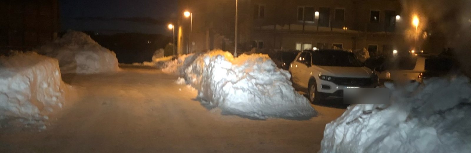 Brøytet vei og oppkjørte snøhauger i et borettslag i Arendal om natten